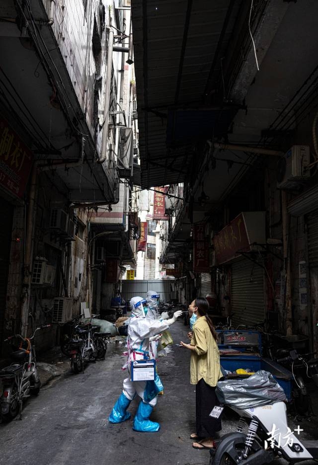 城中村逼仄的握手楼下，网格员们在给片区居民核酸采样。