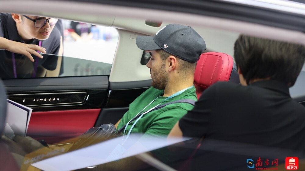 境外采购商正在山西运城一家新能源汽车展位上了解汽车的产地、价格和配置